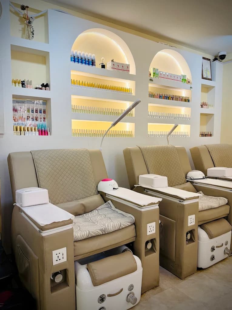 A row of pedicure chairs facing shelves of nail colours in softly lit alcoves